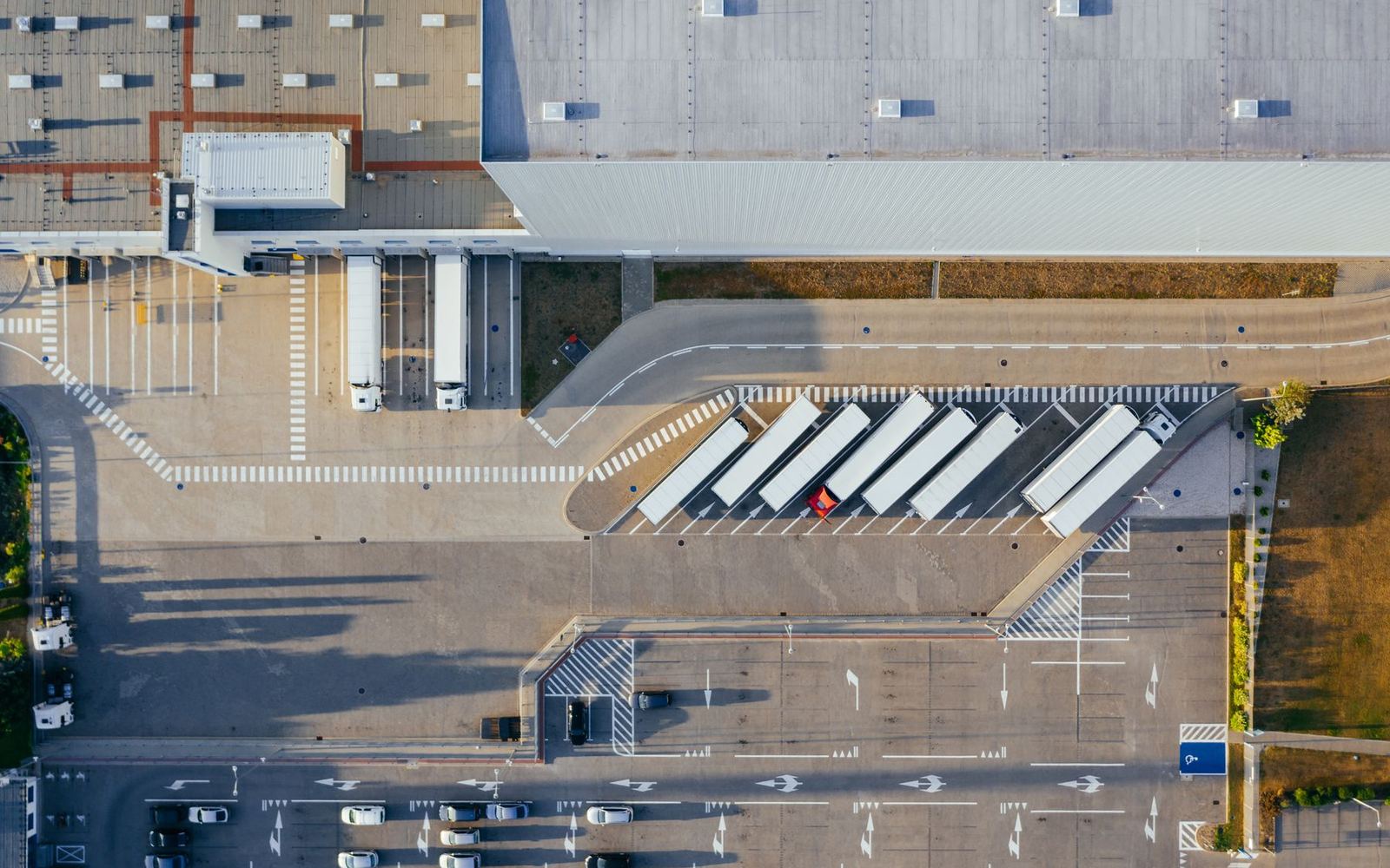A distribution center seen from above, trucks at the loading docks
